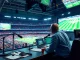 Engaging scene of sports broadcasting with announcer at desk, live games on screens.